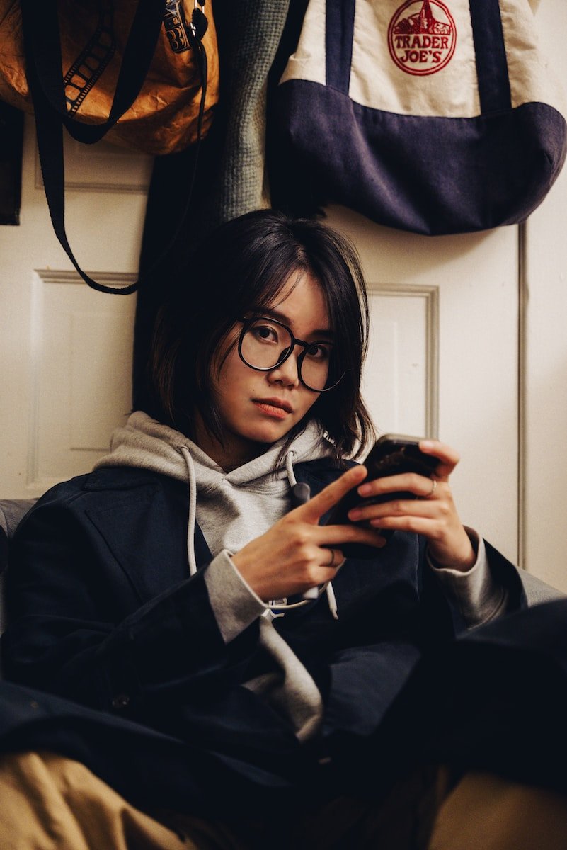 Eine Frau sitzt auf einer Couch und schaut auf ihr Handy